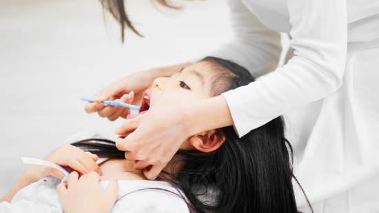仕上げ磨きをしている子どもと親