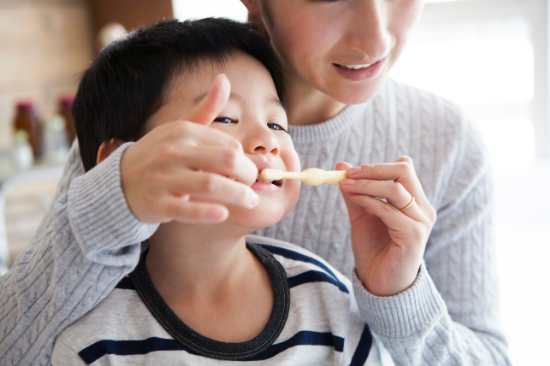 仕上げ磨きをしている子どもと親