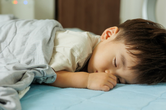 指しゃぶりしながらうつ伏せで寝る子ども