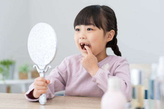 歯並びを鏡で見る女の子