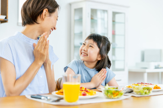 いただきますと手を合わせ微笑み合う親子