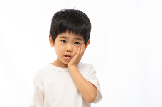 矯正中に違和感を感じて頬を押さえる子供