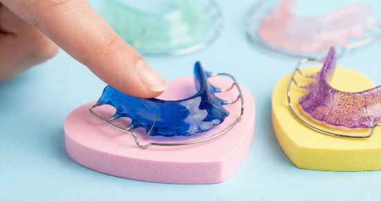 矯正後の後戻りを防ぐためのリテーナーを示す指先