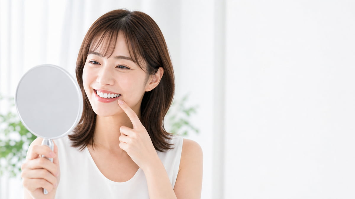 鏡で歯茎の確認をする笑顔の女性